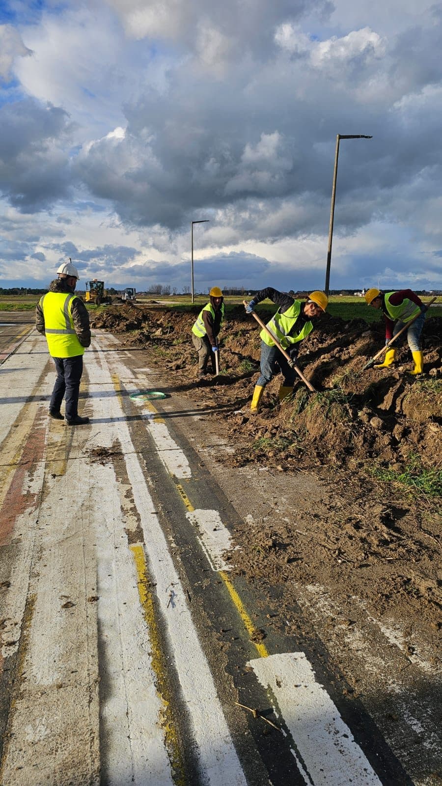Havalimanı sahasında fiber güzergâhı için kanal açan işaretli yelekli montaj ekibi