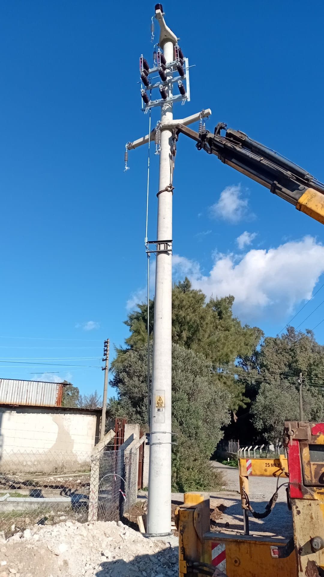 Vinçle yerine dikilen orta gerilim direği ve üzerindeki travers düzeneği